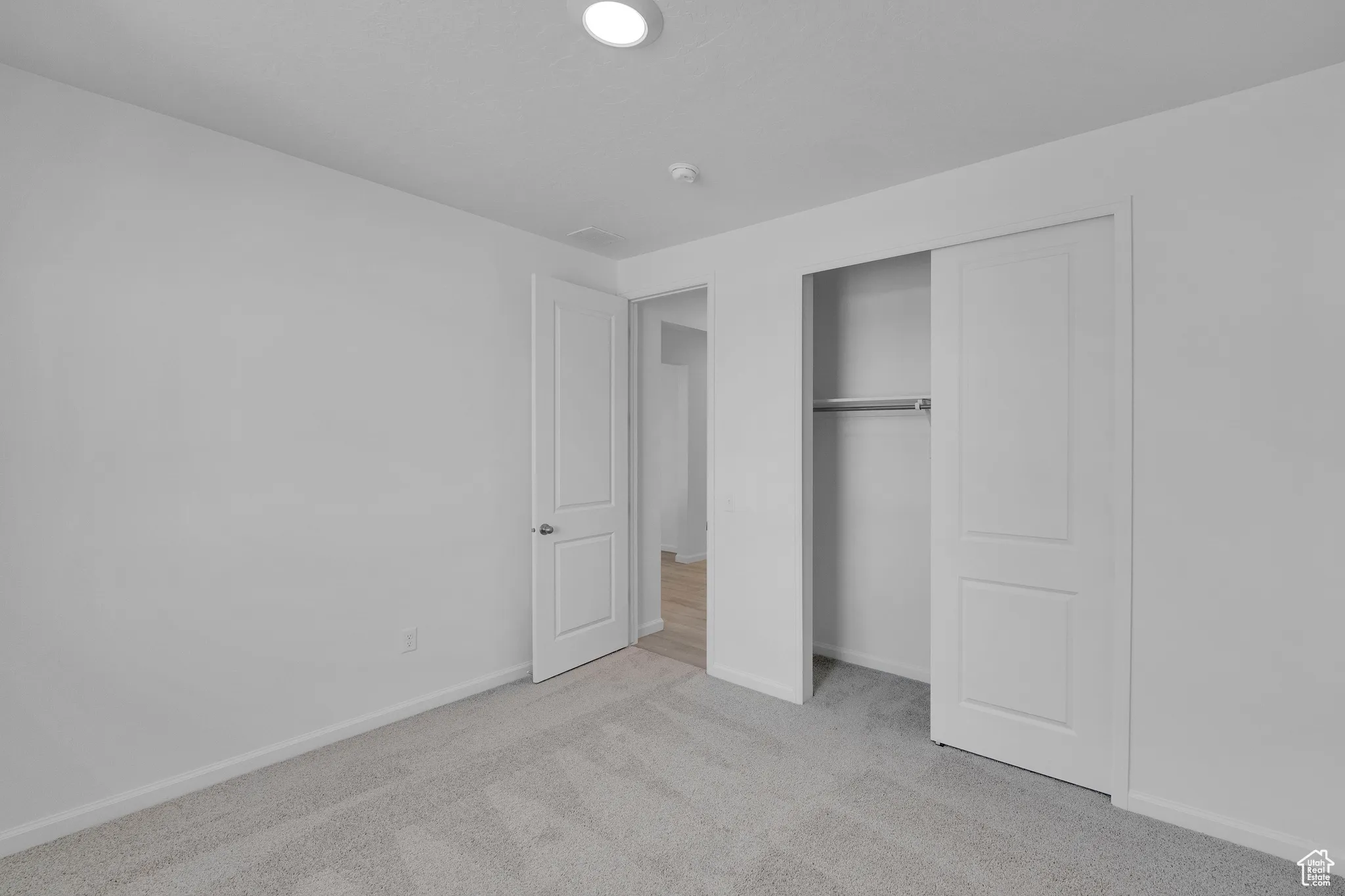 Unfurnished bedroom with light colored carpet and a closet