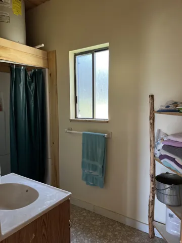 Bathroom featuring a wood-finish vanity with an integrated sink, a frosted-pane window, and textured flooring