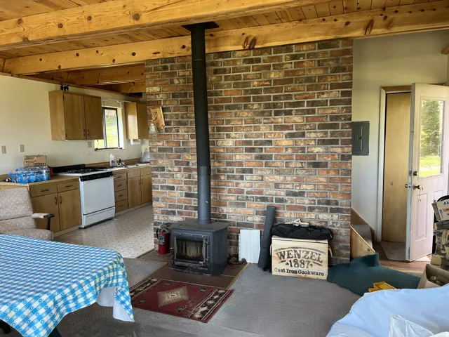 Exposed wood beam ceiling with a rustic brick accent wall featuring a wood-burning stove