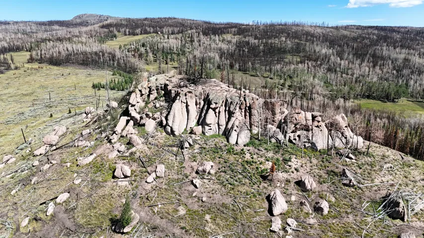 Rocky outcrop featuring prominent boulder formations and scattered vegetation