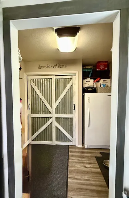 Detailed view of freestanding refrigerator and wood finished floors