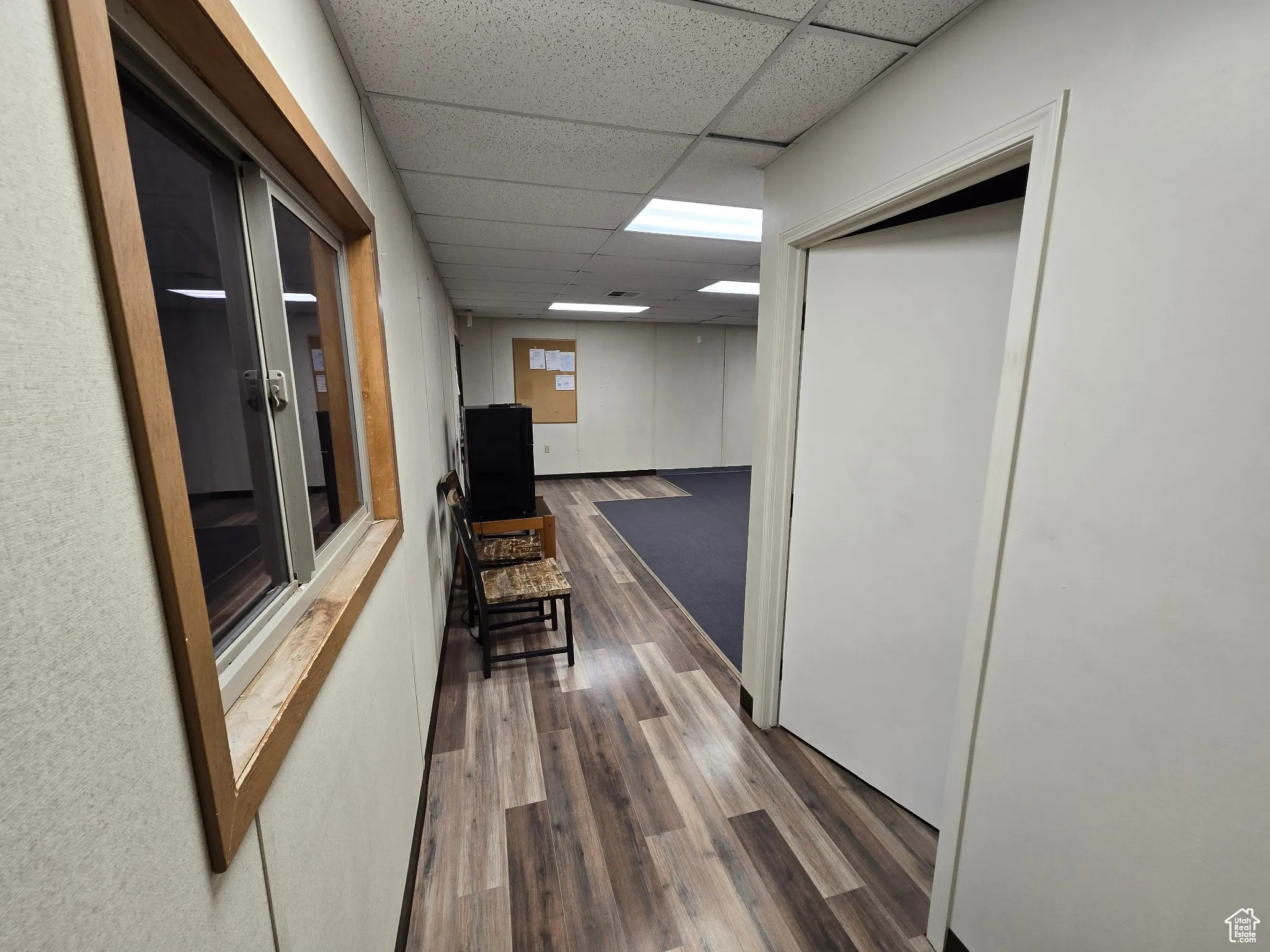 Corridor with a drop ceiling and wood finished floors