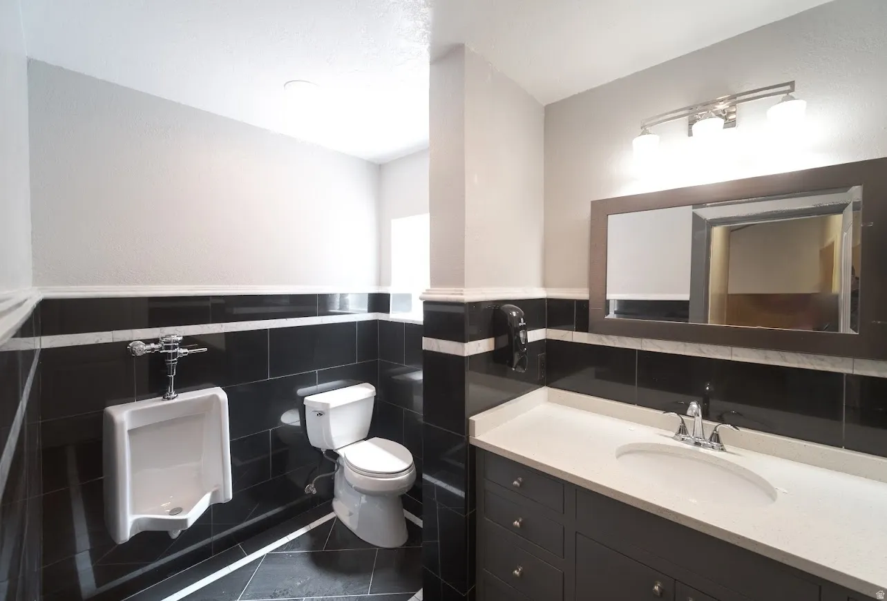 Half bath featuring tile walls, vanity, dark tile patterned floors, and wainscoting