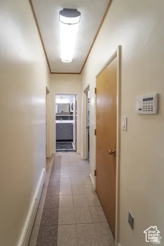 Corridor featuring granite floors, ornamental molding, and baseboard heating