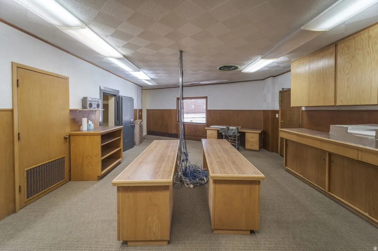 Kitchen with wooden walls, a wainscoted wall, light countertops, a center island, and an office area