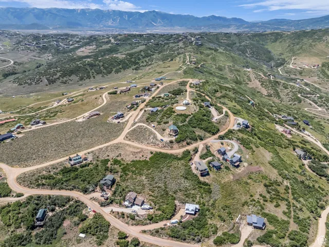 Aerial view of property and surrounding area featuring a mountain backdrop and rural landscape
