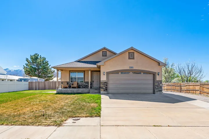 View of front of house featuring stucco siding, covered porch, concrete driveway, an attached garage, and a mountain view