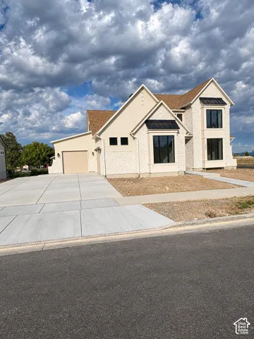 Contemporary residence featuring stucco and brick veneer siding, multiple gables, a two-car garage, and a concrete driveway