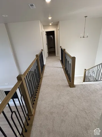 Hallway with recessed lighting, light-toned carpeting, and dark metal balusters with wood-finish handrails