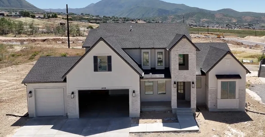 French provincial home with a mountain view, driveway, stucco siding, and a shingled roof