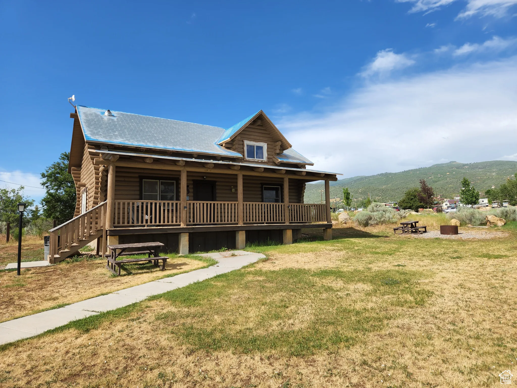 View of front of property with covered porch, a front lawn, a mountain view, and log siding