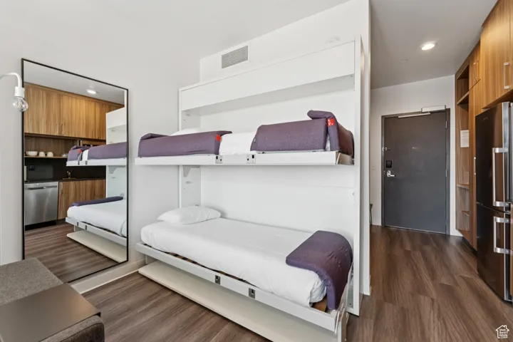 Bedroom featuring freestanding refrigerator, dark wood-type flooring, and recessed lighting