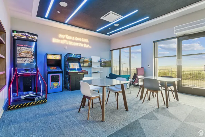 Rec room featuring carpet flooring, a tray ceiling, a wall unit AC, and plenty of natural light