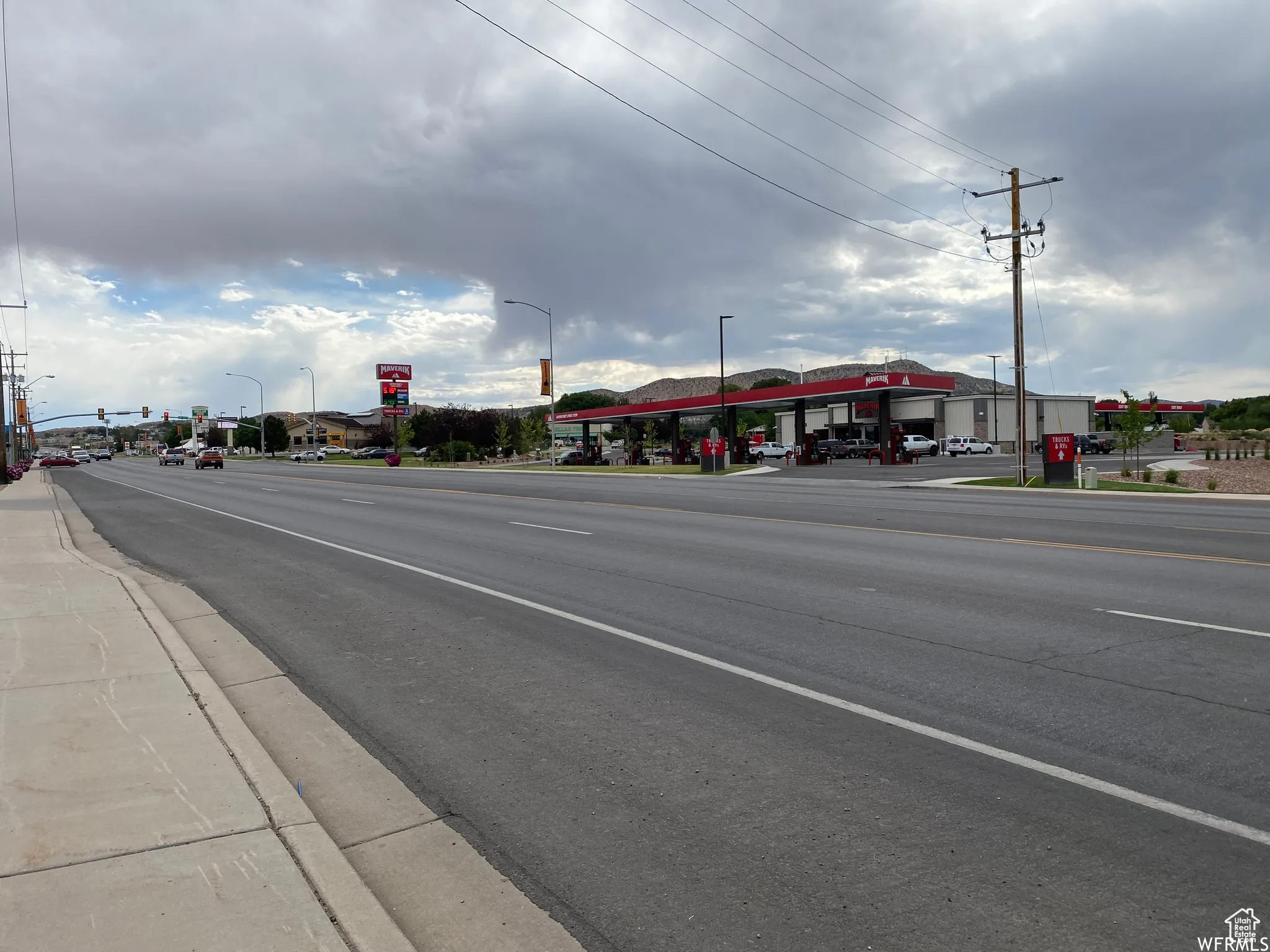 View of asphalt road with sidewalks, street lighting, and curbs