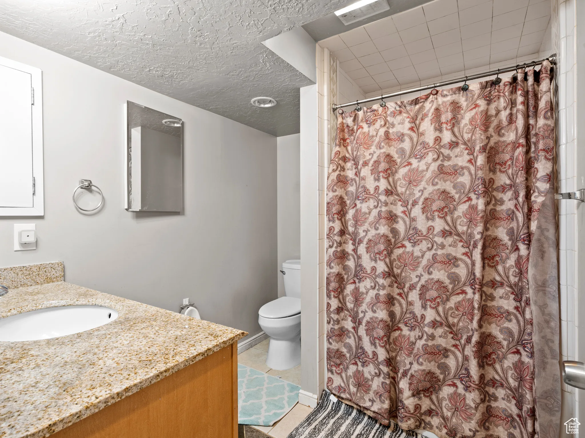 Bathroom with vanity, curtained shower, and a textured ceiling