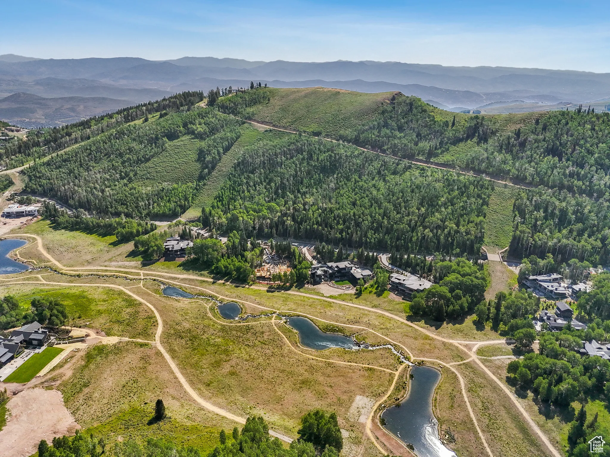 Aerial overview of property's location with a water and mountain view and a forest