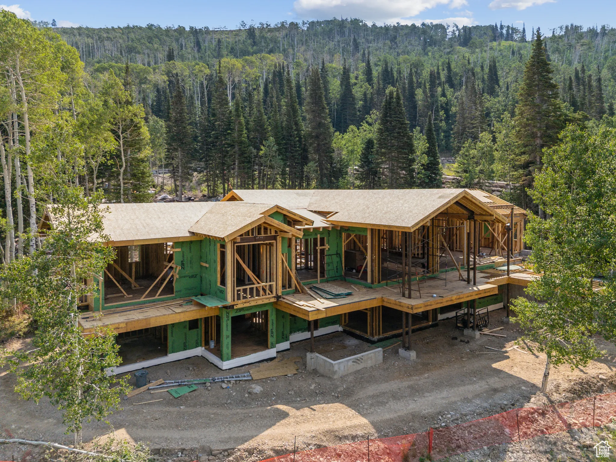 Back of house with a view of trees and a shingled roof