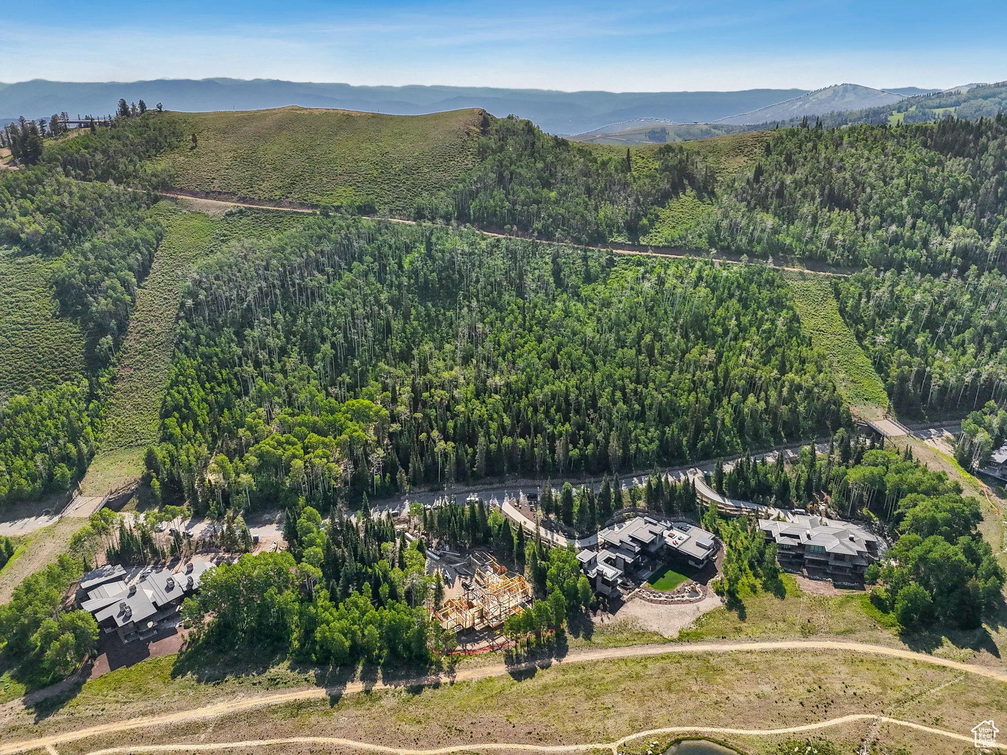 Aerial view of property and surrounding area featuring a heavily wooded area and a mountainous background