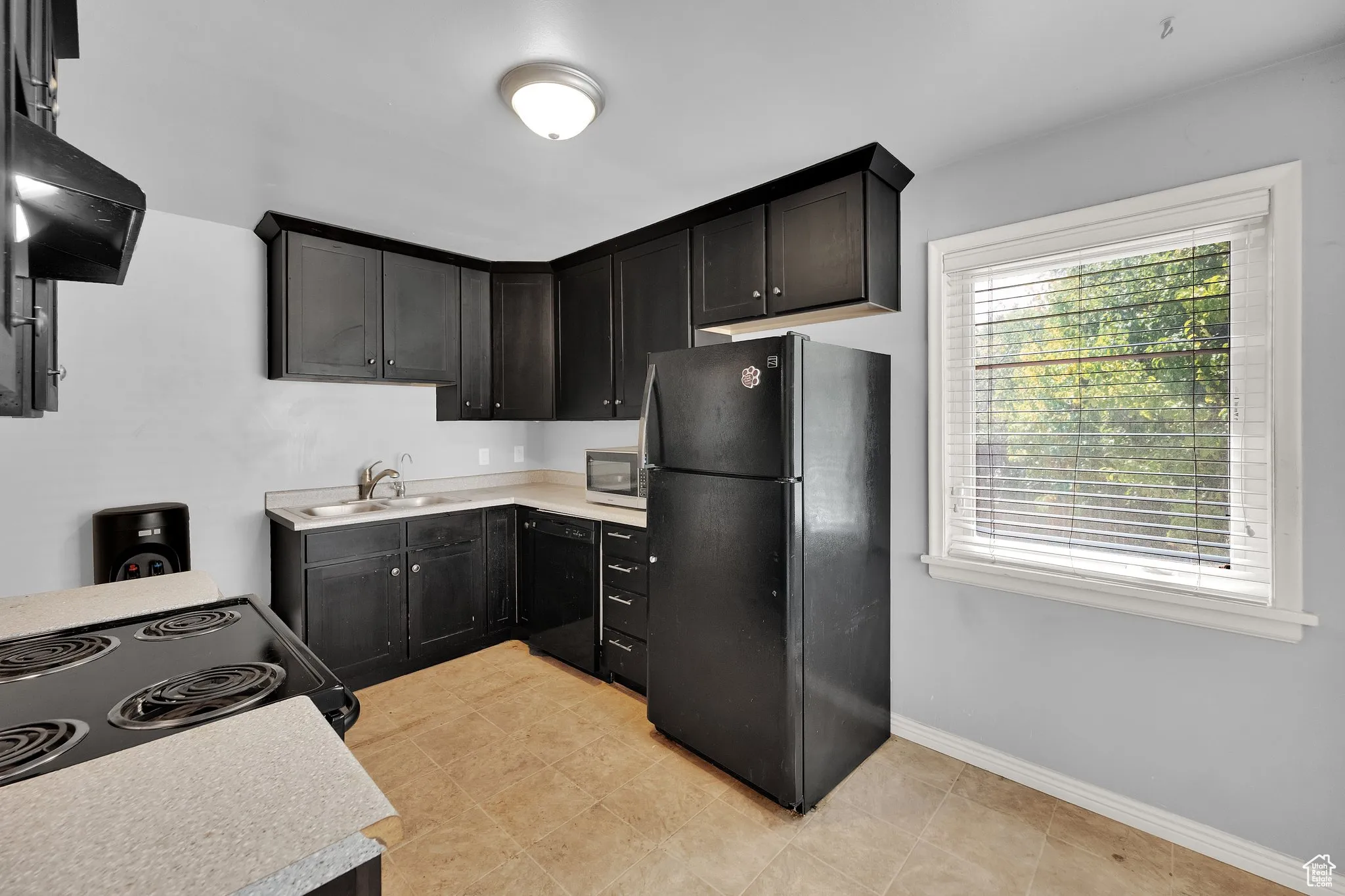 Kitchen with black appliances, healthy amount of natural light, light countertops, and ventilation hood