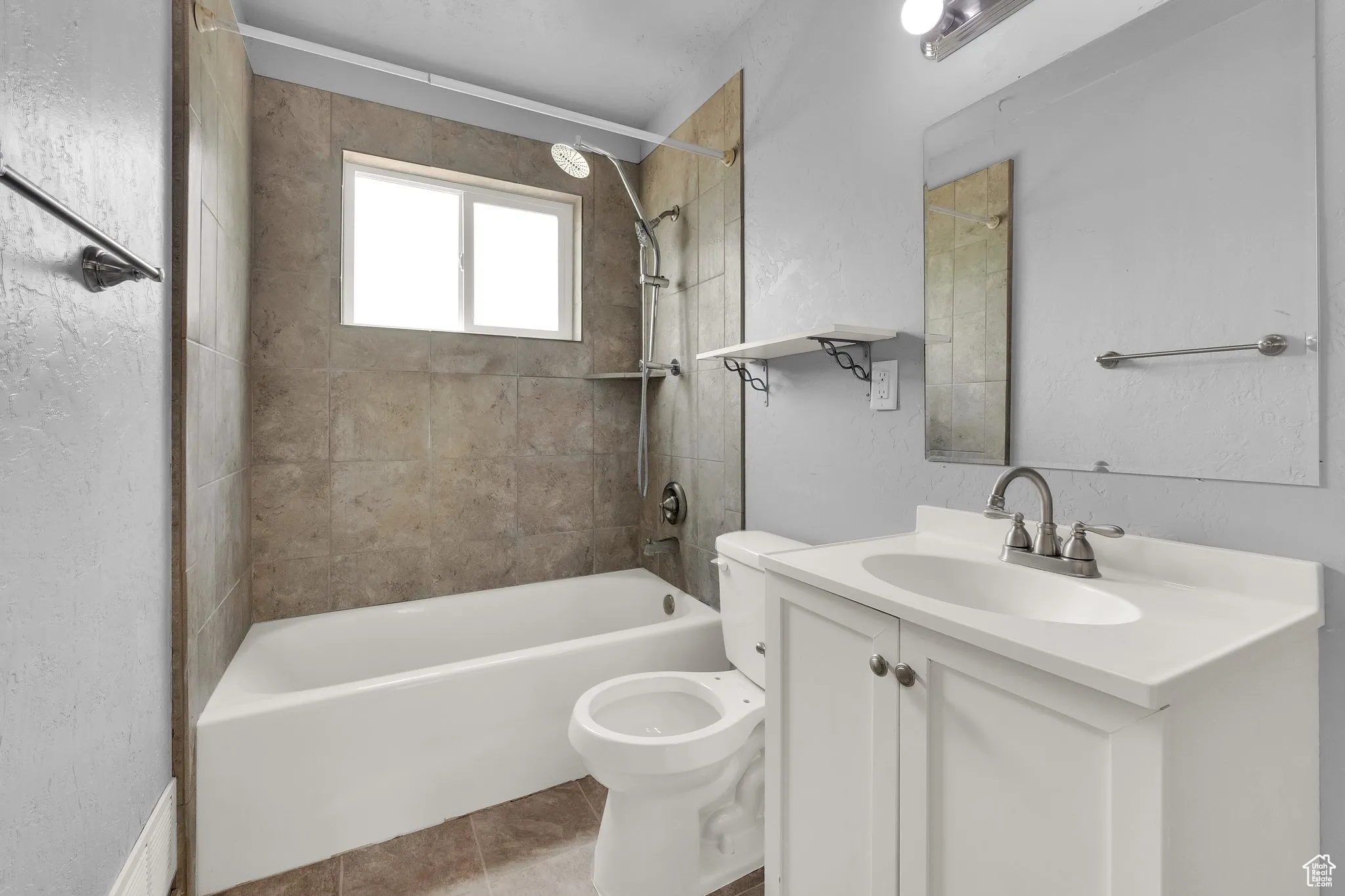Full bath featuring bathtub / shower combination, vanity, tile patterned flooring, and a textured wall