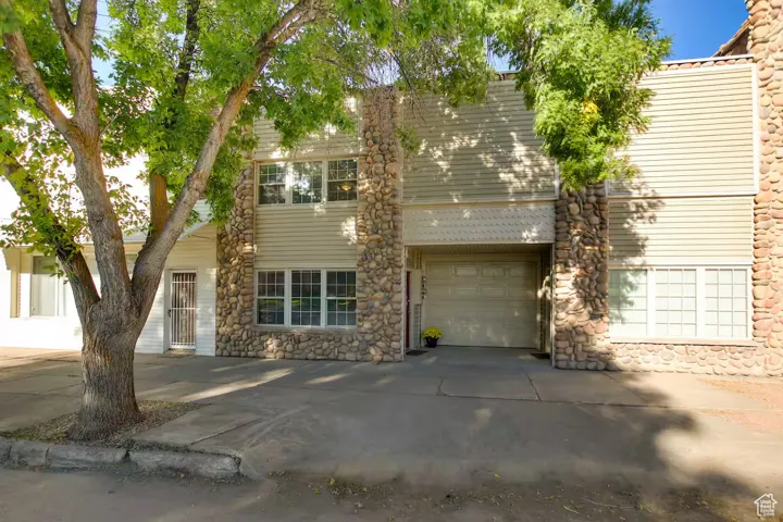 View of front of house featuring stone siding and concrete driveway