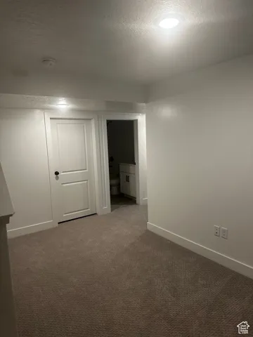 Empty room featuring a textured ceiling and dark colored carpet