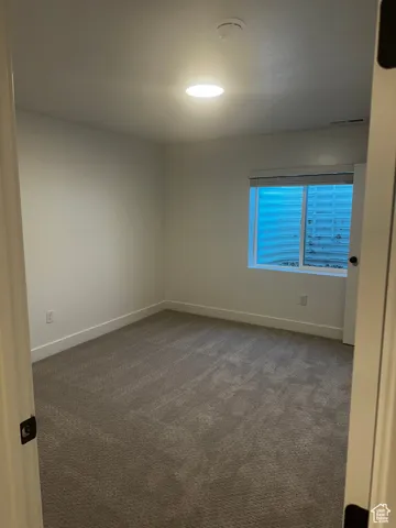 Empty room with carpet floors and a smoke detector