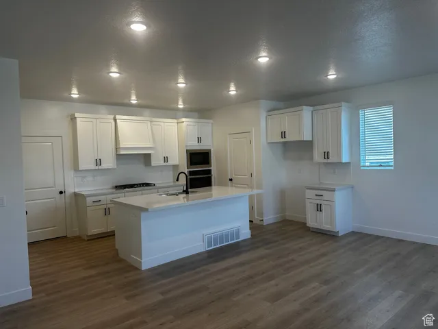 Kitchen featuring built in microwave, oven, gas stovetop, dark wood finished floors, and a textured ceiling