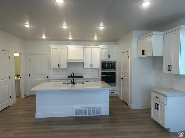 Kitchen with appliances with stainless steel finishes, white cabinetry, decorative backsplash, recessed lighting, and a textured ceiling