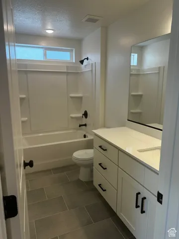 Full bathroom featuring vanity,  shower combination, a textured ceiling, and tile patterned floors