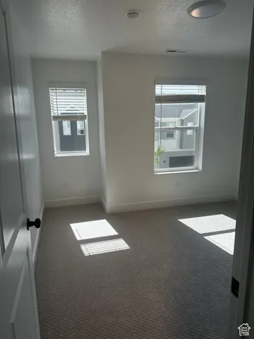 Spare room with a textured ceiling, carpet flooring, healthy amount of natural light, and a smoke detector