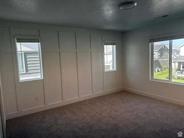 Carpeted spare room with a textured ceiling and baseboards