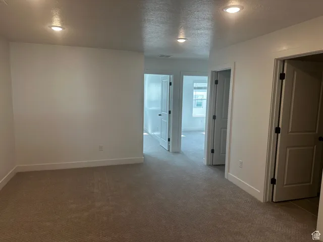 Unfurnished room featuring a textured ceiling and carpet floors