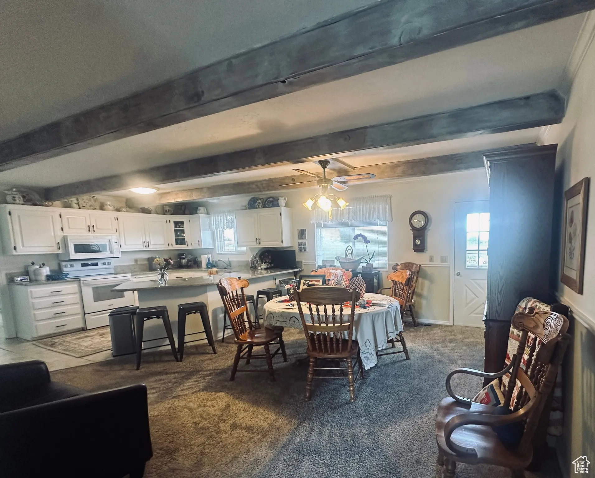 Carpeted dining room with healthy amount of natural light, beamed ceiling, and a ceiling fan