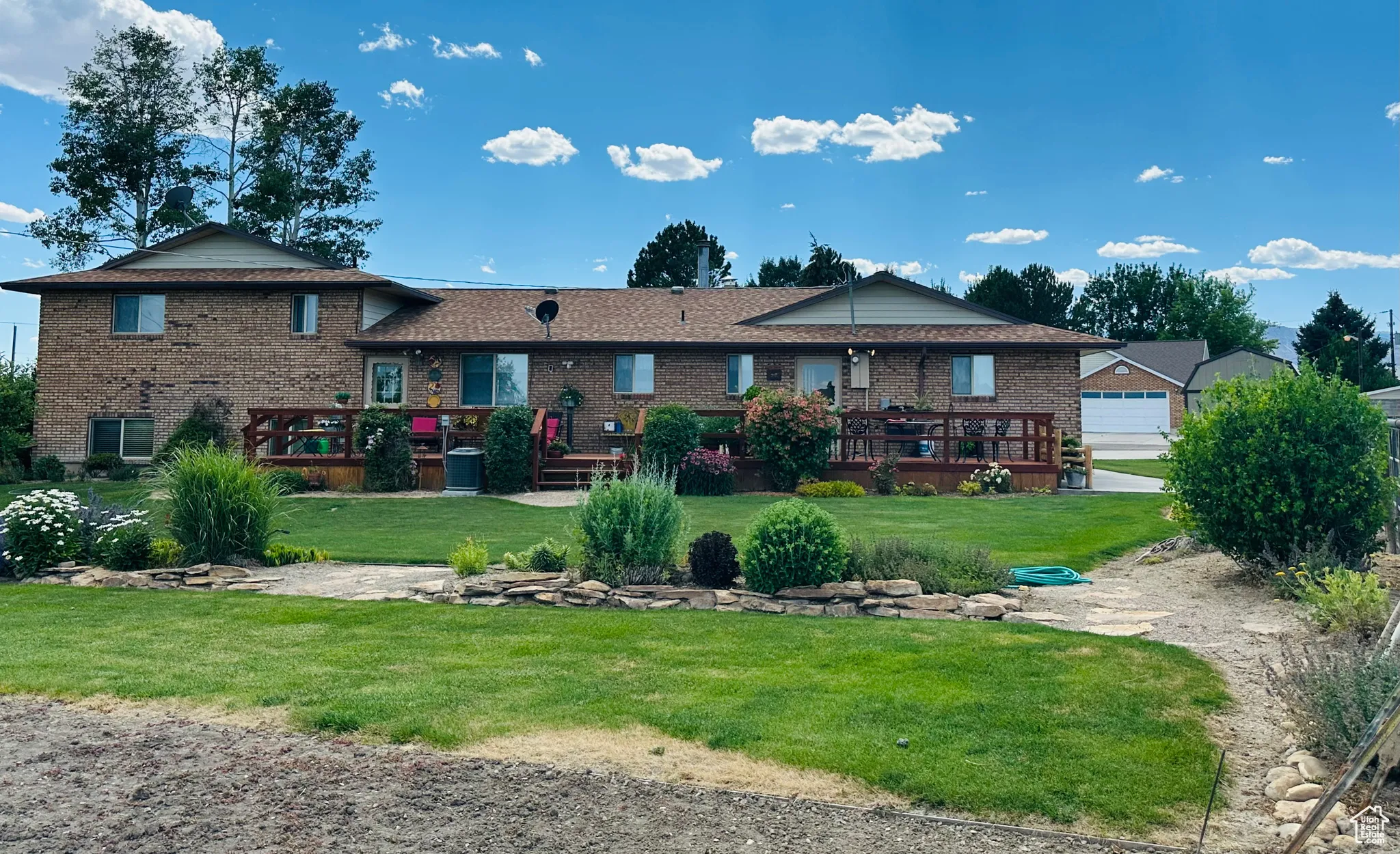 Back of property featuring brick siding, a wooden deck, and a yard