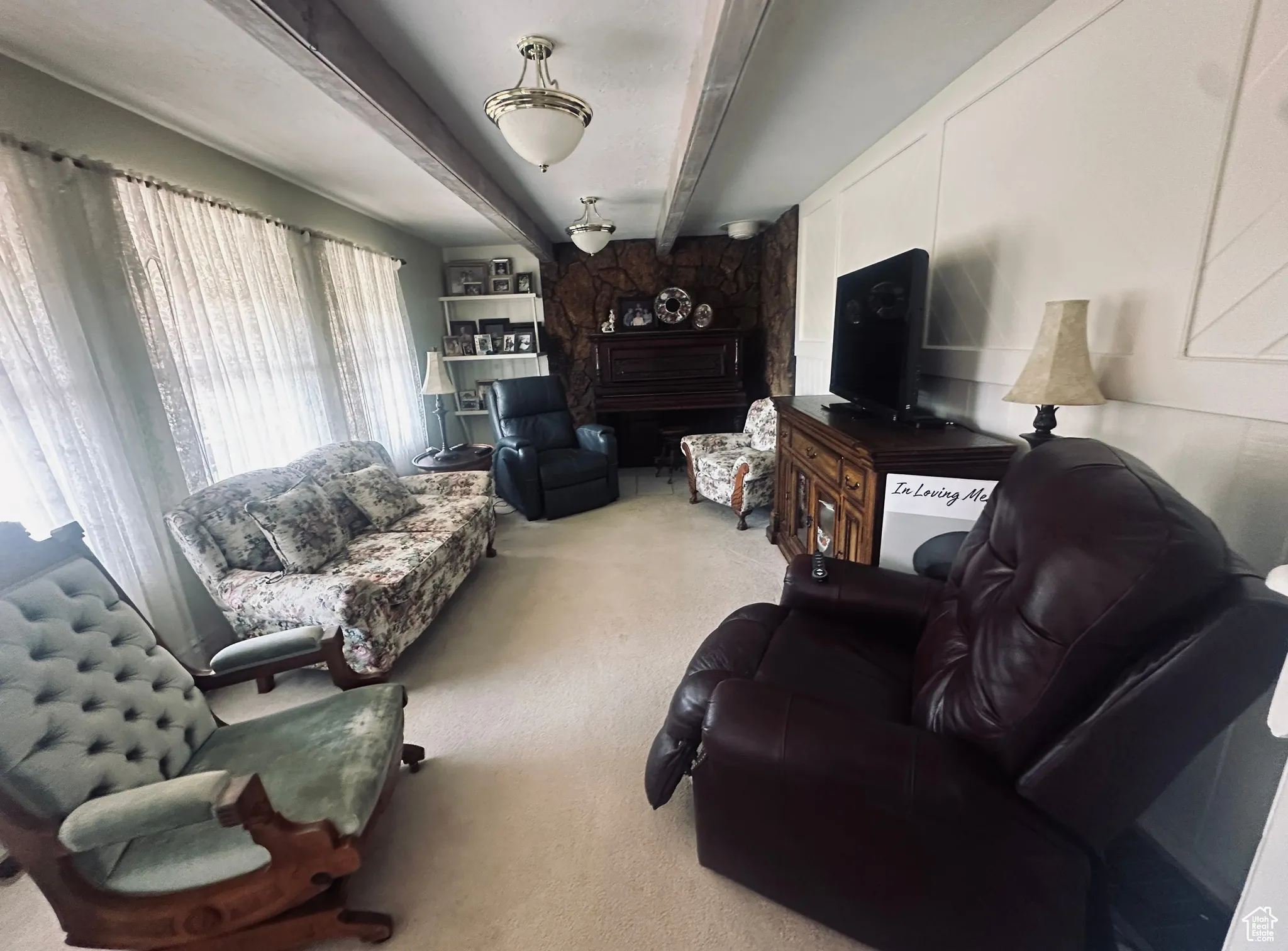 Living area with carpet floors and beam ceiling