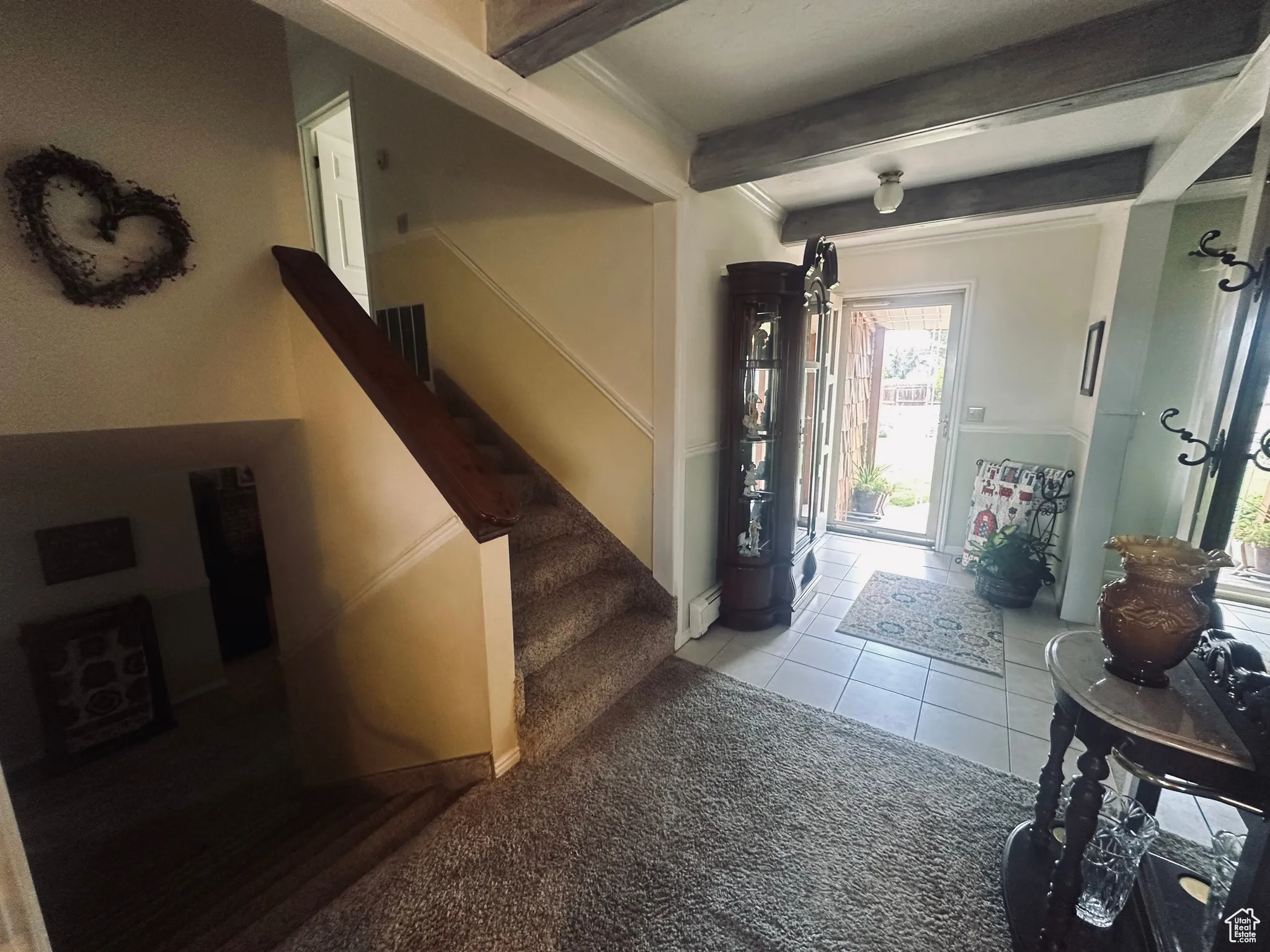 Carpeted entryway featuring beamed ceiling, stairs, and tile patterned floors