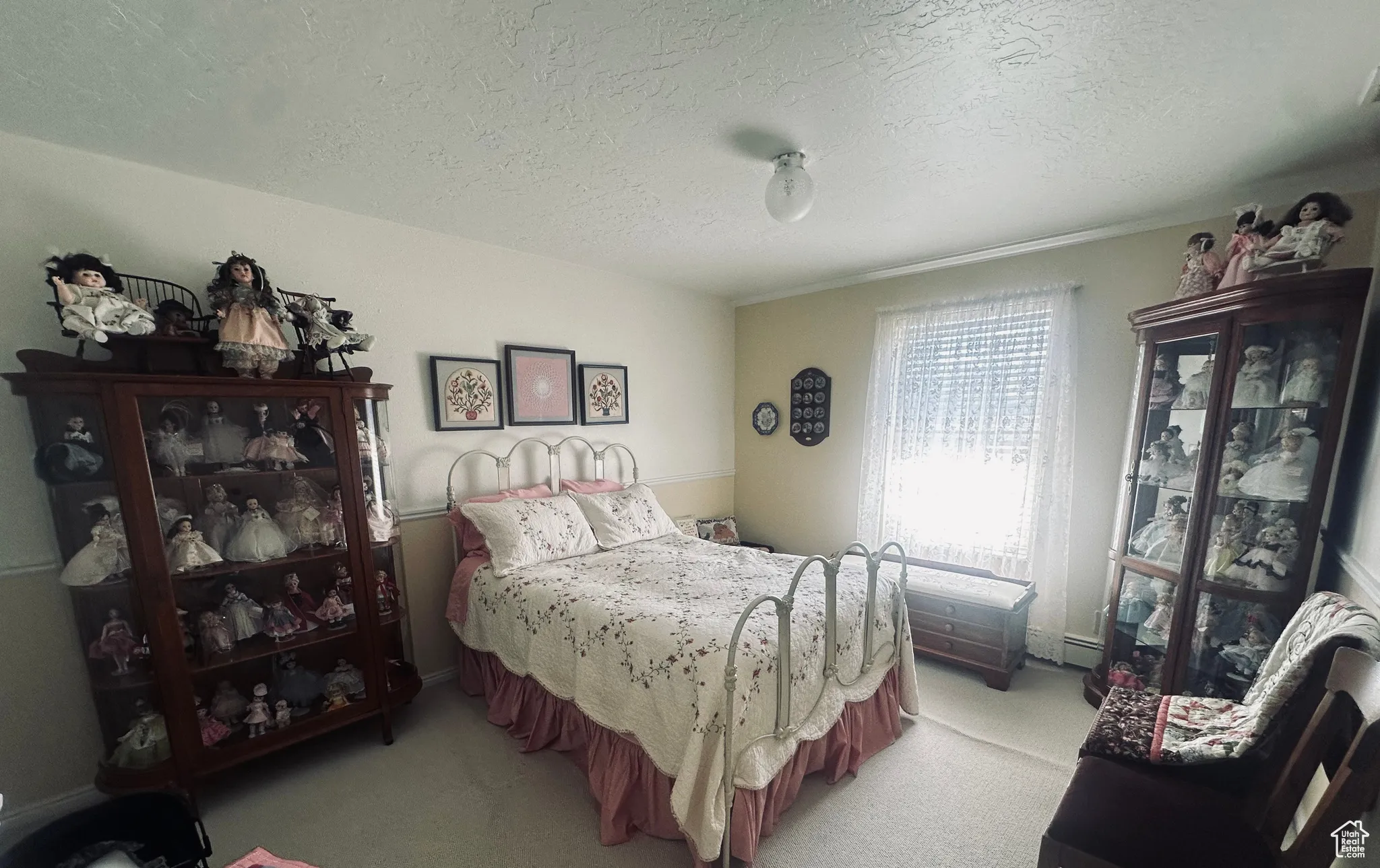 Bedroom with a textured ceiling, light colored carpet, and baseboard heating