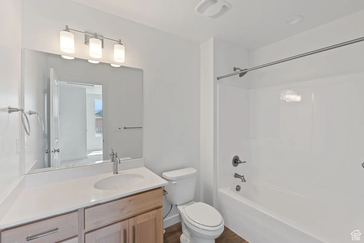 Bathroom with vanity, shower / tub combination, and wood finished floors