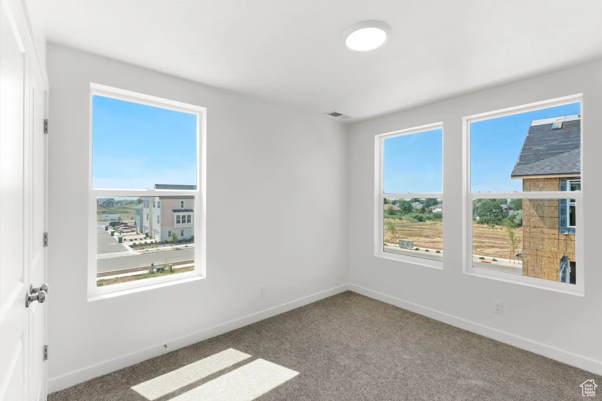 Carpeted spare room featuring baseboards