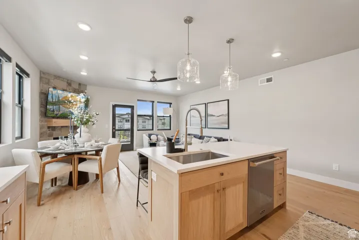 Kitchen featuring light brown cabinets, dishwasher, open floor plan, light wood-type flooring, and recessed lighting