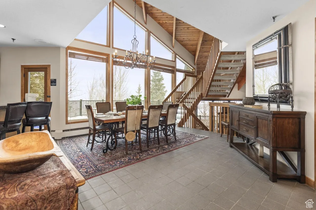 Dining room featuring a chandelier, stairway, and tile patterned floors