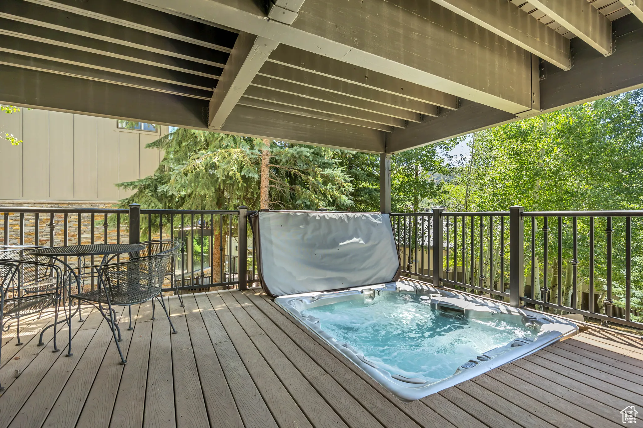 Wooden terrace with a covered hot tub and outdoor dining space