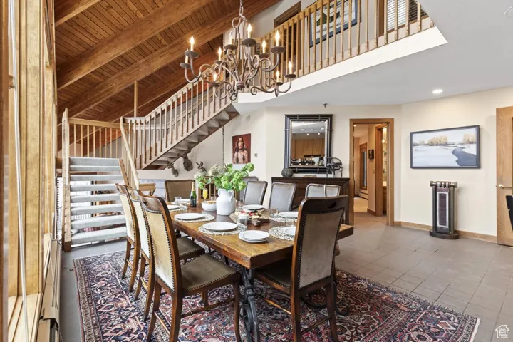 Dining room featuring stairs, a wood ceiling with exposed beams, tile patterned flooring, a chandelier, and recessed lighting