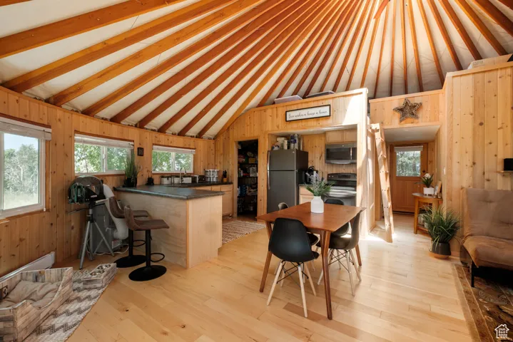 Kitchen with stainless steel appliances, vaulted ceiling, wooden walls, dark countertops, and a peninsula