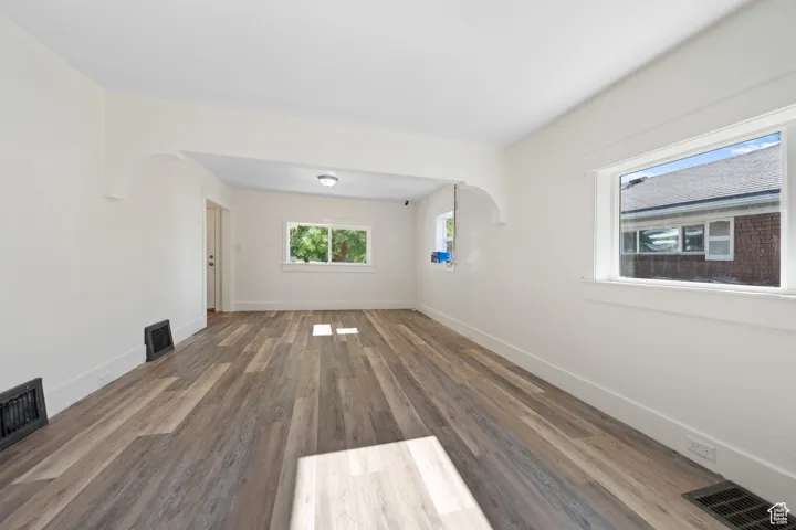 Unfurnished living room with arched walkways and wood finished floors