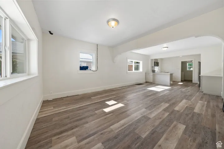 Unfurnished living room featuring arched walkways and wood finished floors