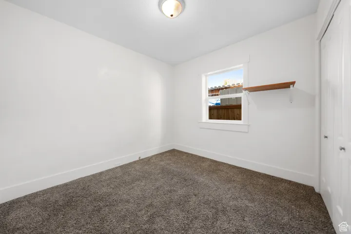 Empty room with dark carpet and baseboards