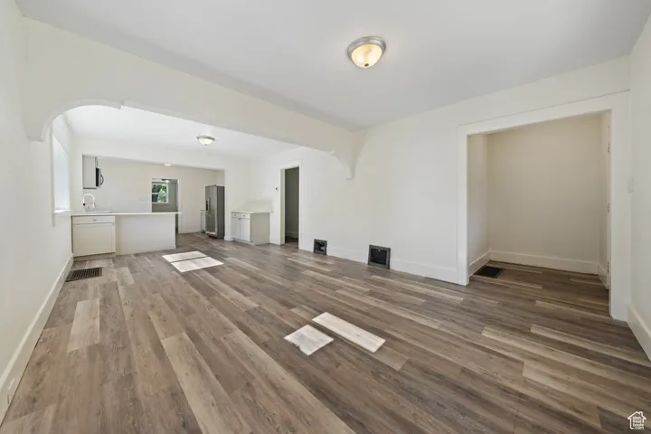Unfurnished living room featuring dark wood finished floors and arched walkways