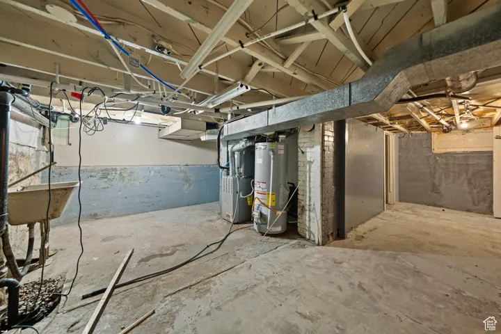 Unfinished below grade area featuring gas water heater and heating unit